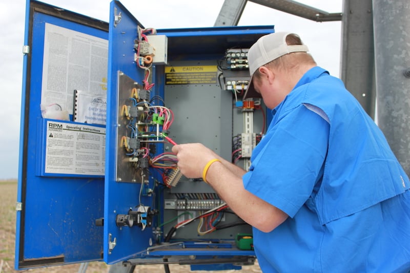 man checks pivot irrigation control box
